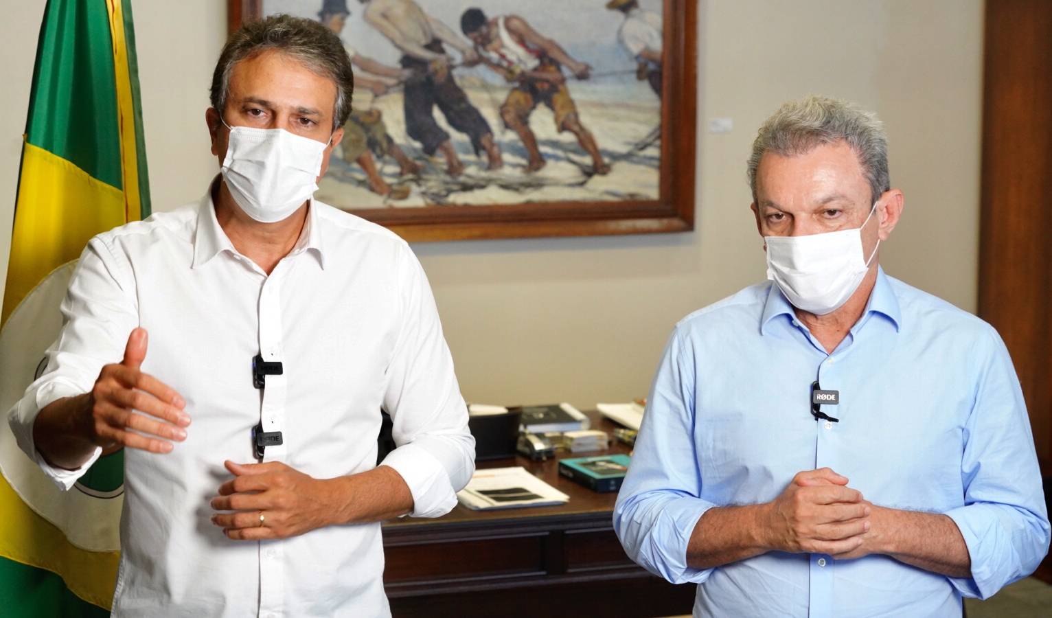 Governador e prefeito, com máscara, falam ao microfone